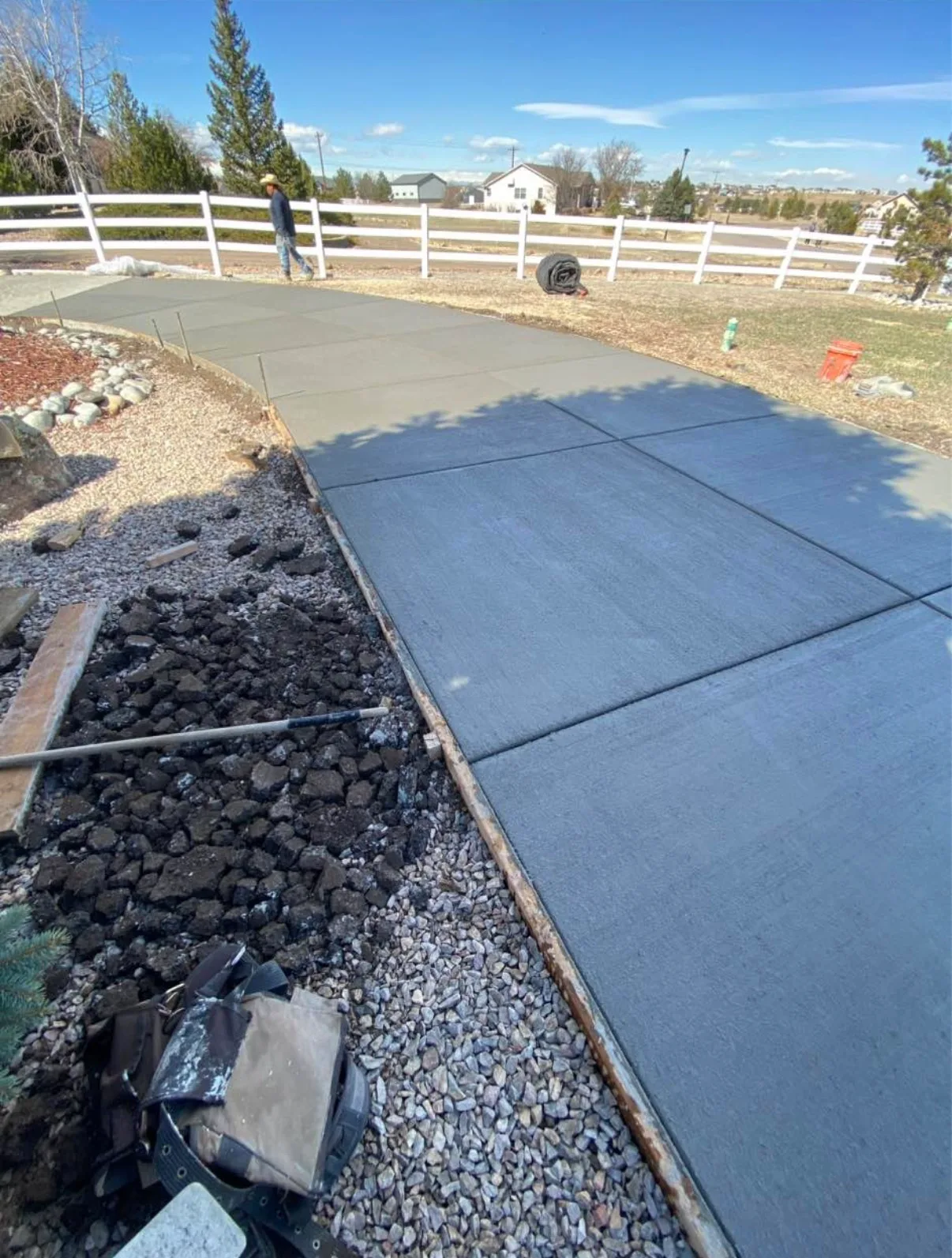 Dark stamped concrete walkway laid beside a black rock bed