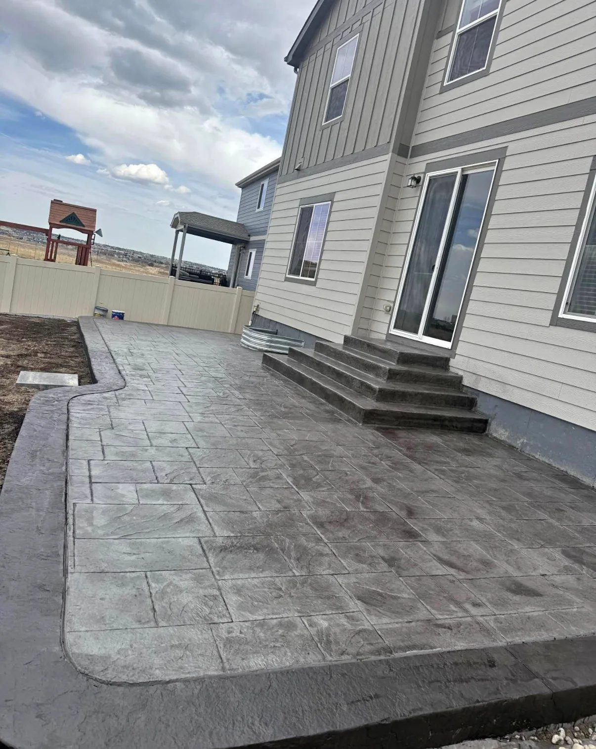 Concrete patio and steps at the back of a grey sided house