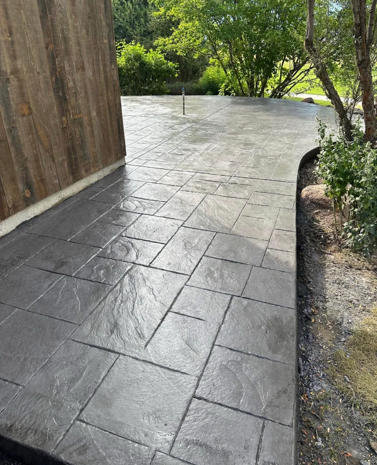 Stamped concrete walkway curving along a house toward a side gate