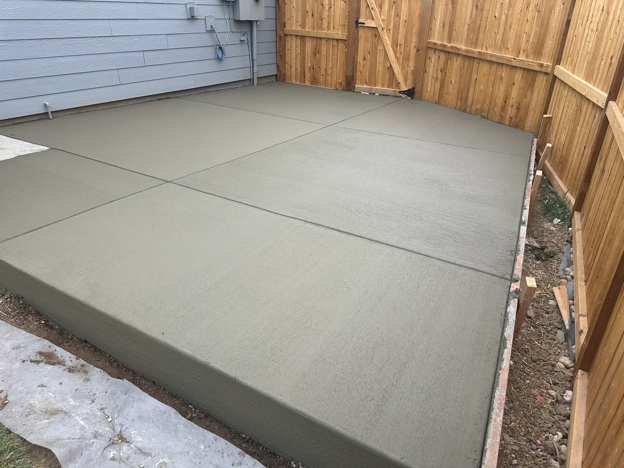 Broad concrete patio slab poured up to a cedar fence line