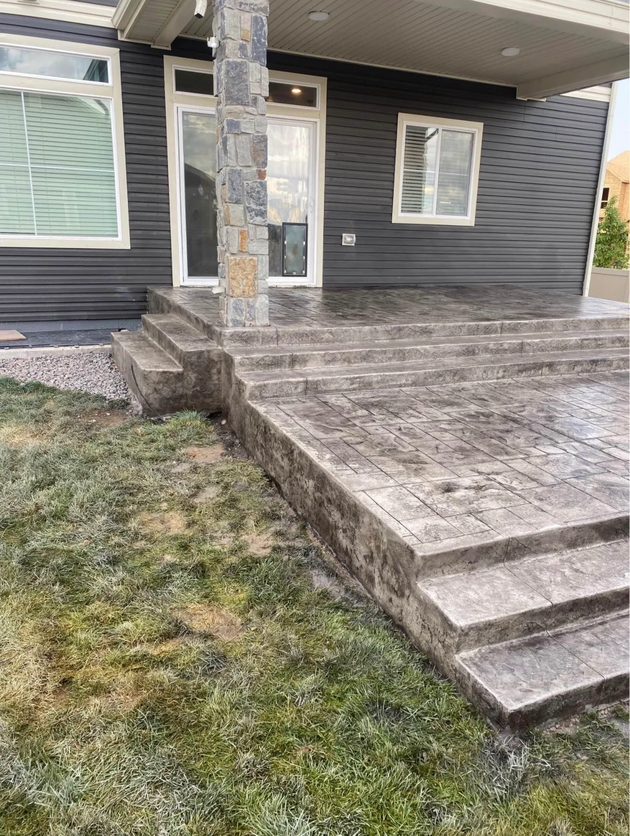 Stamped concrete patio and steps at the back of a grey house