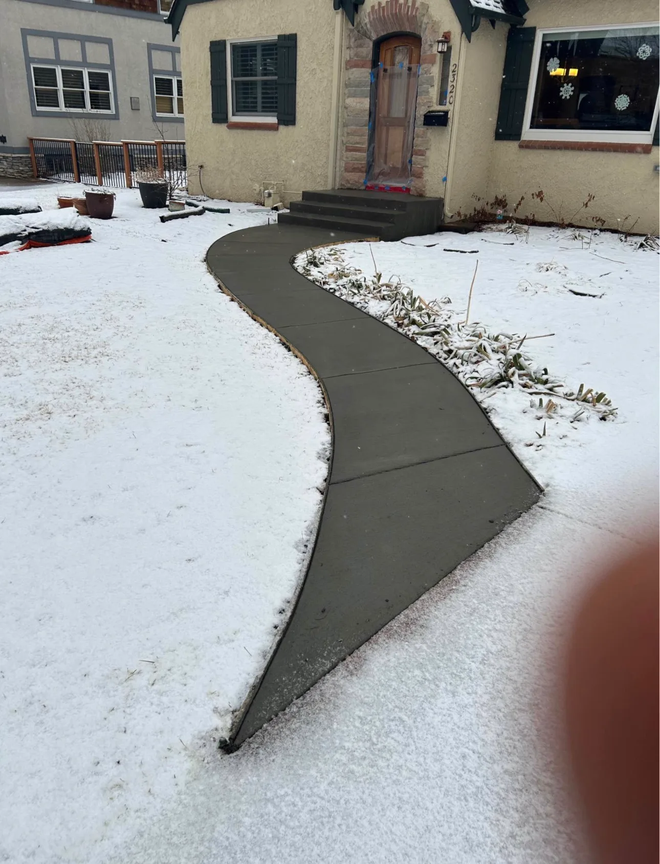 Curved concrete walkway poured and finished with snow still on the ground