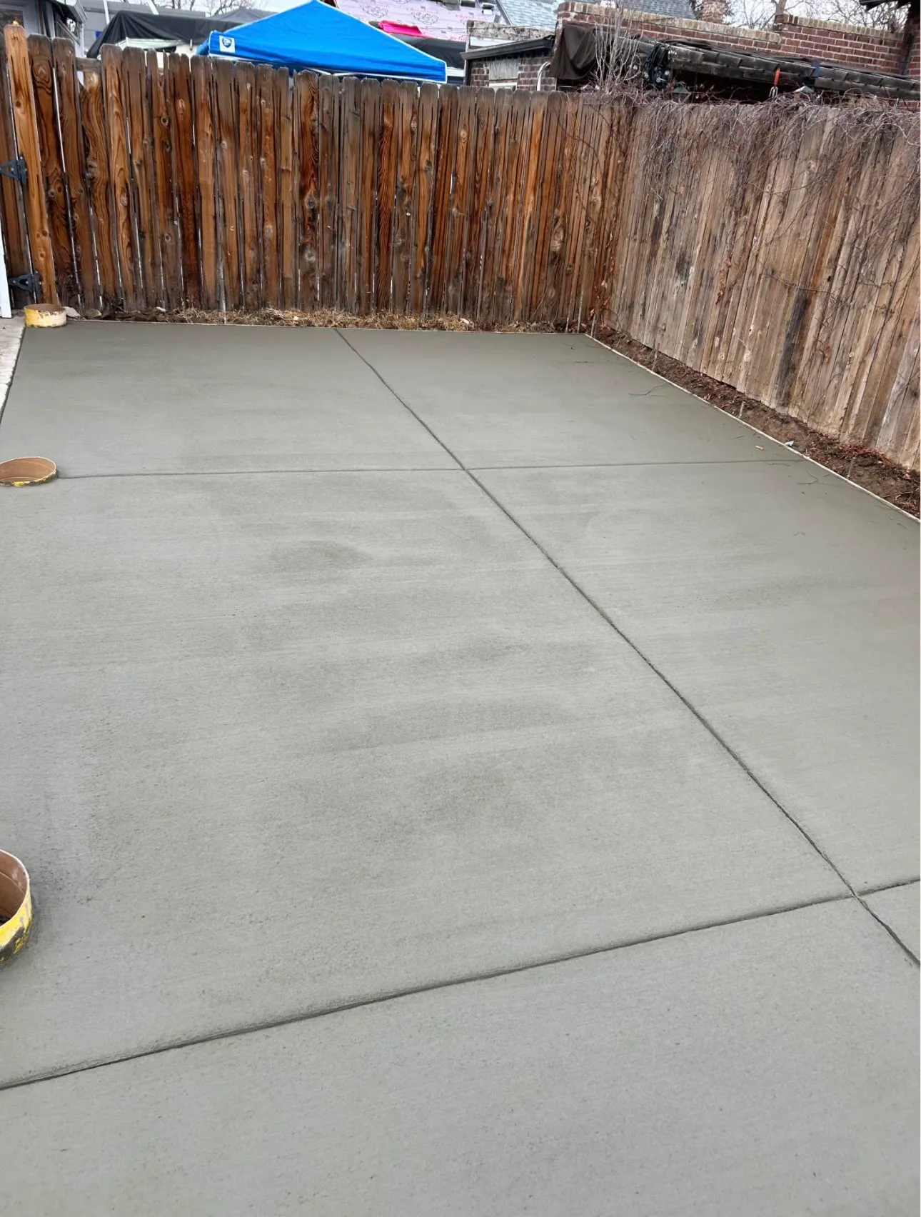 Long concrete patio running the length of a fenced back yard