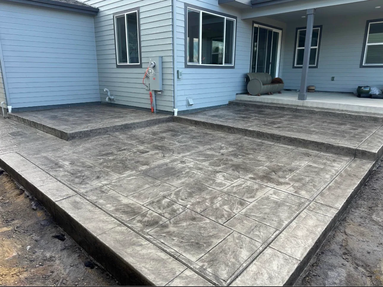 Stamped concrete patio laid against a light blue sided house