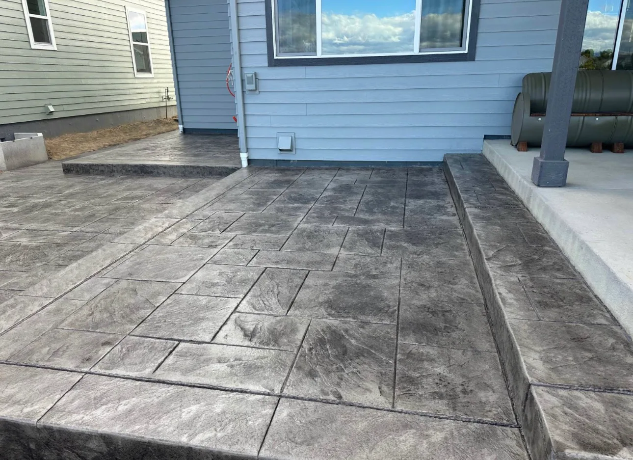 Stamped concrete patio joining a walkway along a house