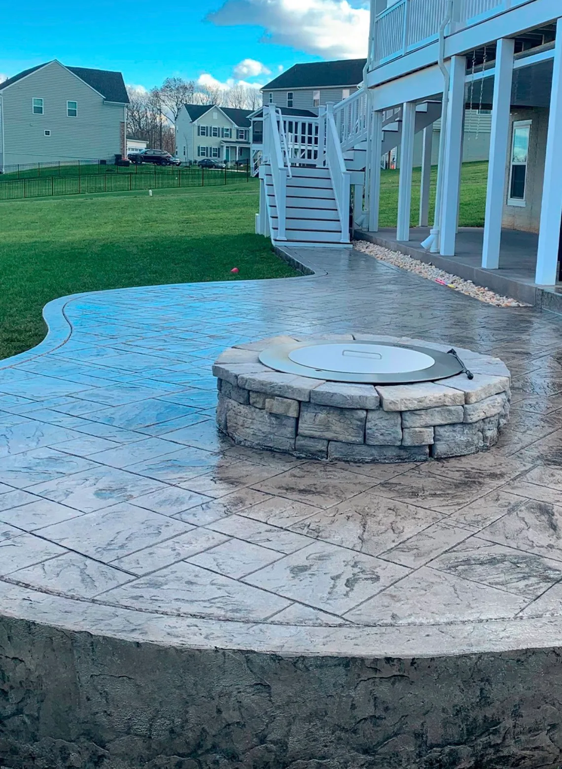 Stone fire pit built on stamped concrete beside a swimming pool