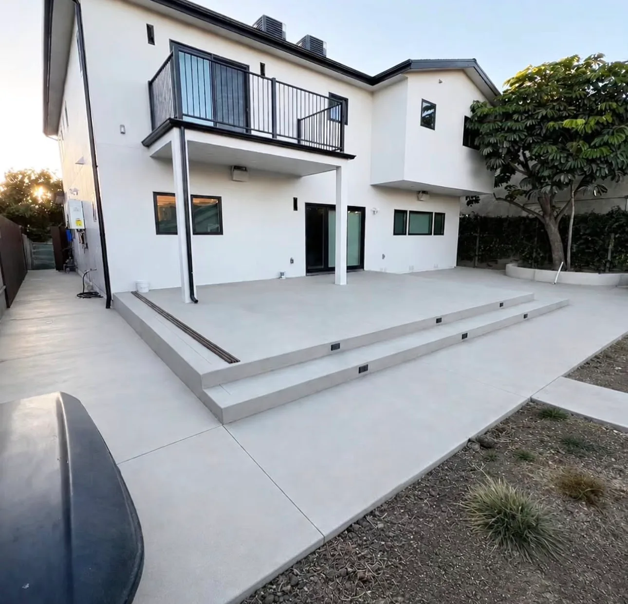 Concrete patio and steps behind a white modern home