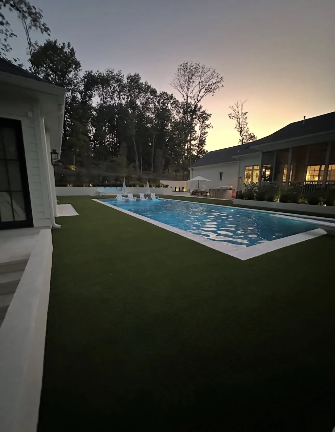 Artificial turf lawn running up to a pool deck at dusk