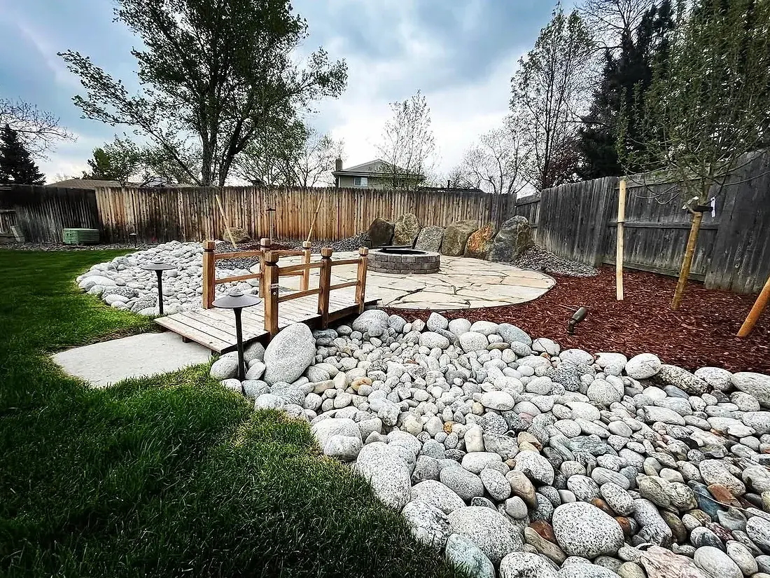 River rock bed and lawn in a finished Colorado back yard