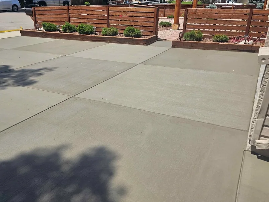 Concrete driveway beside cedar planter walls and a horizontal slat fence