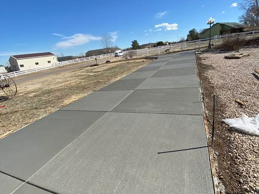 Long wide concrete driveway leading to a ranch style house