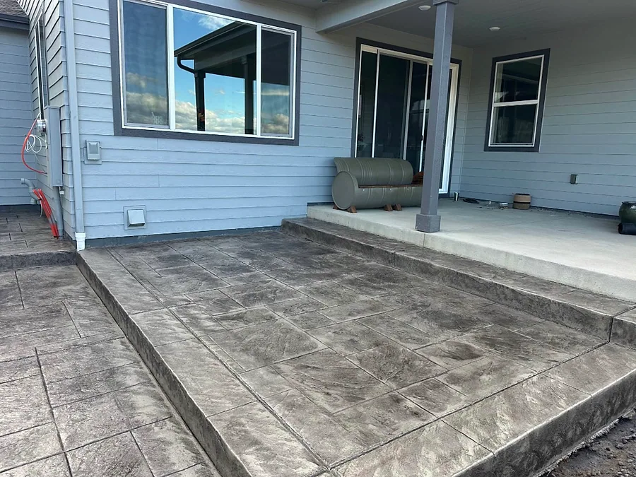 Stamped concrete patio under a covered porch at the back of a house