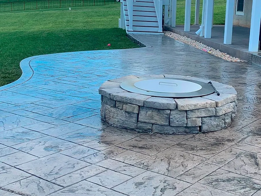 Round stamped concrete patio built around a stone fire pit