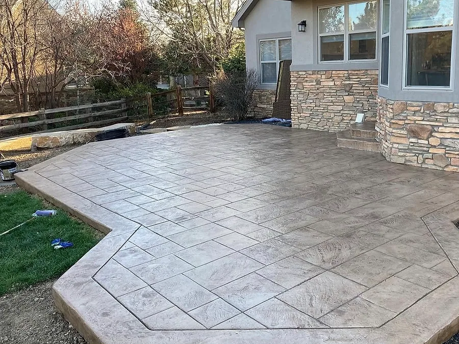 Octagonal stamped concrete patio behind a stone fronted home